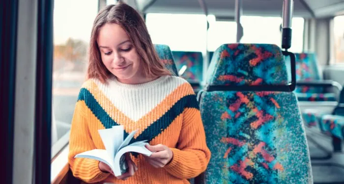 a person smiling and reading on the bus