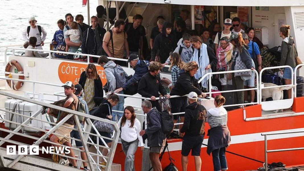 A number of passengers disembark from a boat